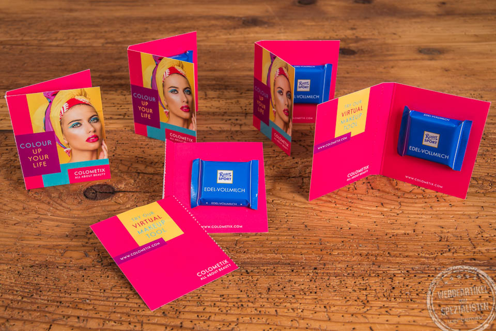 Sechs Werbekarten als Streuartikel in pinker Farbe gefüllt mit blauer Ritter Sport Vollmilch Schokolade.