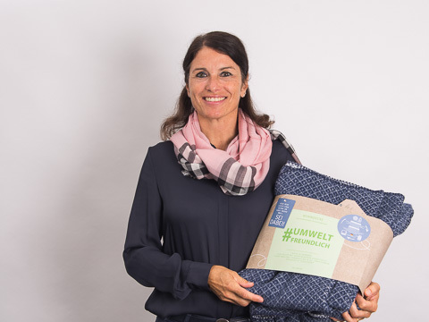 Britta Unterreitmeier Manager Online-Marketing mit einer blauen Decke als Werbegeschenk in den H&auml;nden. 