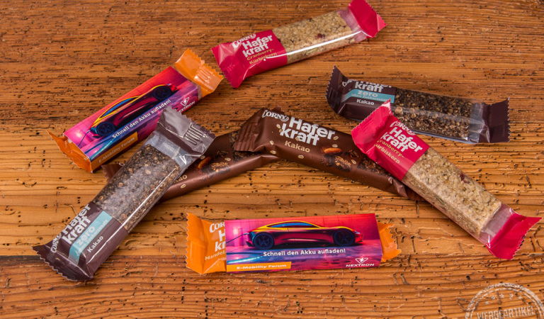 Müsliriegel von Corny im bedruckten Werbeschuber als leckerer Werbeartikel für alle Zielgruppen. 