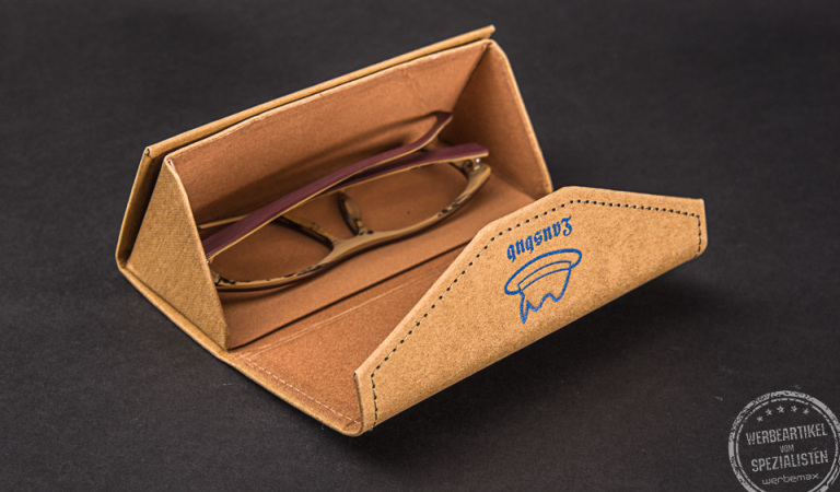 Ein Brillenetui aus Kraftpapier mit Logodruck als Werbegeschenk auf schwarzem Hintergrund.