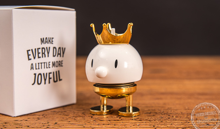 Hoptimist Wackelfigur mit Krone und Geschenkkarton als Werbeartikel.