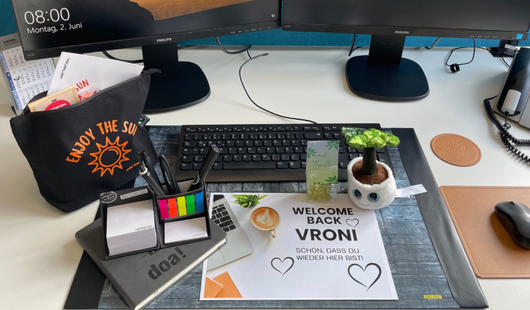 werbemax Schreibtisch mit Onboarding-Werbeartikel wie z.B. ein Schmoozie Evergreenies Displaycleaner, Stifte, Süßigkeiten im Blockbeutel, Kosmetiktasche mit Newkee-Sonnencreme 