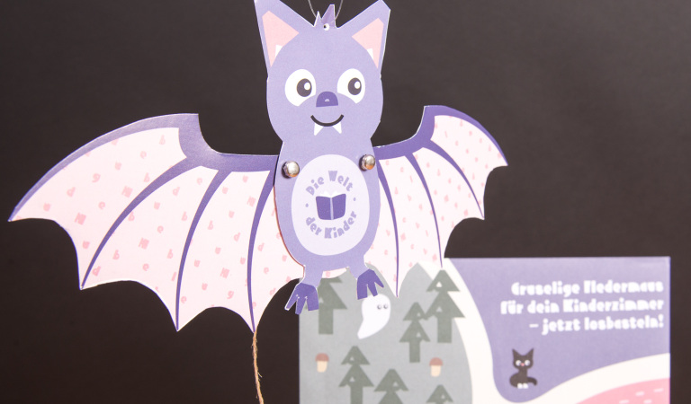 Gebastelte lila Fledermaus aus dem Halloween-Bastelset für Kinder, umgesetzt als kreativer Werbeartikel für Hugendubel.