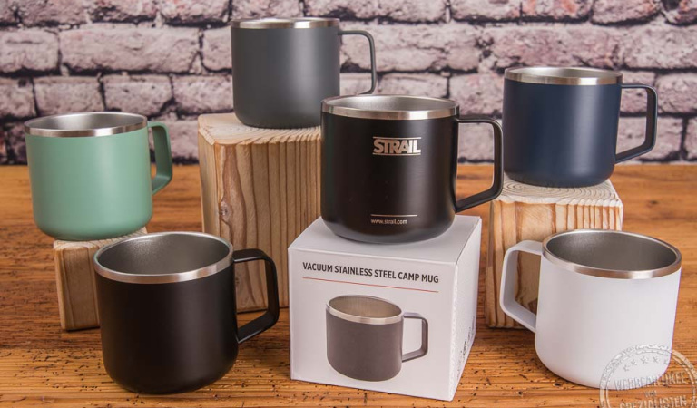Edelstahl Becher in Weiss, Schwarz, Grau und Blau mit Einzelverpackung und Logogravur auf Holztisch.