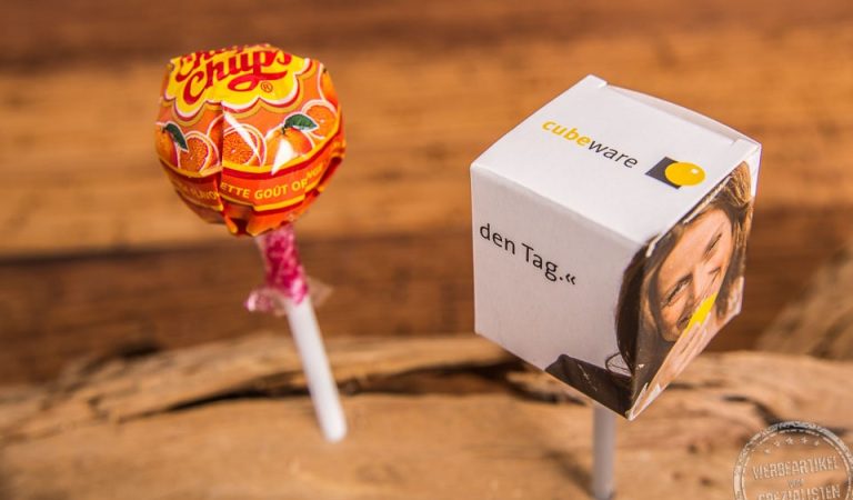 Chupa Chups Lolly in bedruckter Box als Werbeartikel  steckt in Holzplatte.