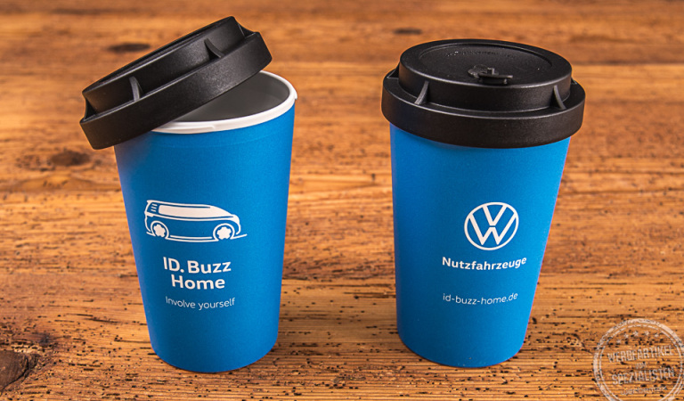 Zwei blaue Coffee-to-go Becher mit Logoaufdruck ID. Buzz Home als Werbegeschenk für Volkswagen.