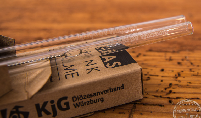 Glas-Trinkhalme mit Logo in Geschenkverpackung KjG auf Holztisch