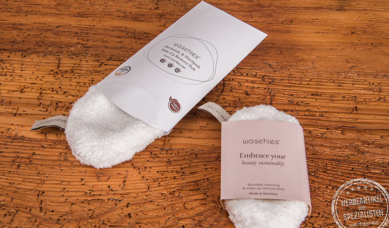 Zwei wiederverwendbare Abschminkpads Waschies mit bedruckter Kissenverpackung und Banderole als Werbeartikel.