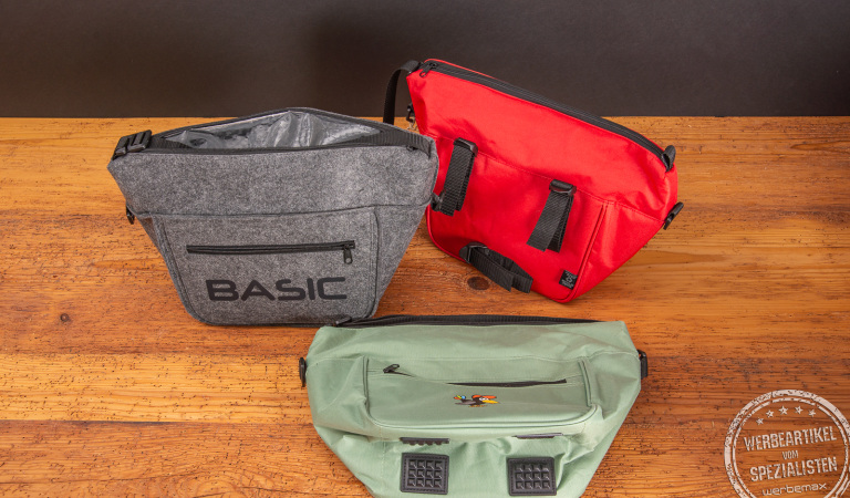 Kühltasche für Outdoorfans, Lunchbag in den Farben grau, rot und weiß als praktische Kühltasche mit Fahrradbefestigung. Hier mit großem Logodruck in schwarz auf der grauen Lunchbag. 