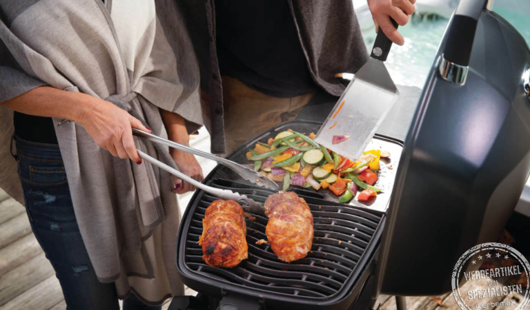 Napoleon Grill belegt mit Grillgut und Grillzubehör.