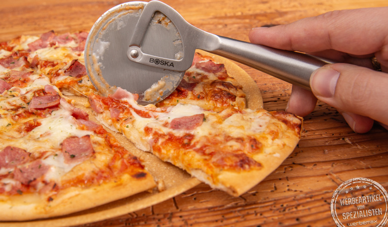 Detailaufnahme des Pizzaschneiders Boska mit Lasergravur als Werbegeschenk auf Holzunterlage