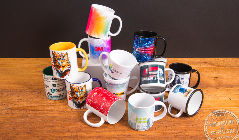 Bunte Tassen mit individuellen Fotomotiven und Logos als kreative Werbeartikel – bedruckte Kaffeebecher von Werbemax auf einem Holztisch arrangiert.