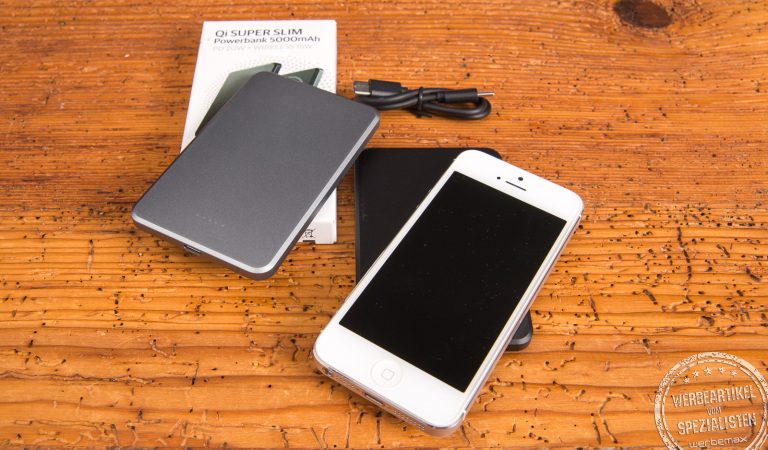 Qi Super Slim Powerbank als Werbeartikel – Set mit Smartphone, USB-Kabel und Verpackung auf Holztisch
