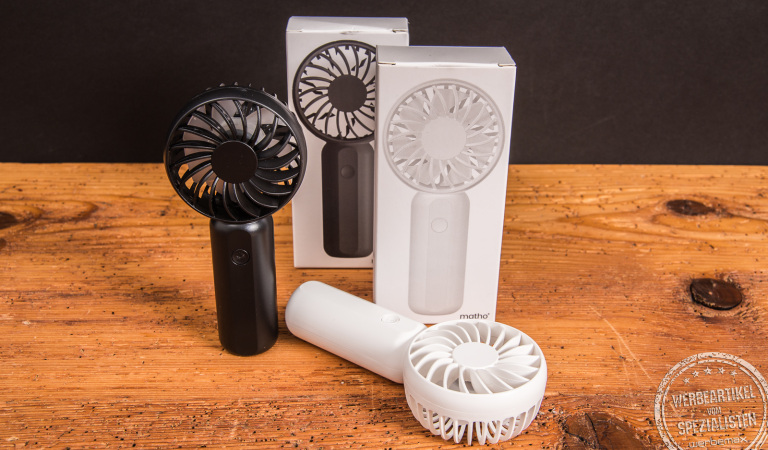 Handventilator Breezy als Werbeartikel in Schwarz und Weiß mit Logo-Fläche, jeweils mit Einzelverpackung – modernes Sommer-Promotion-Geschenk auf Holzplatte.