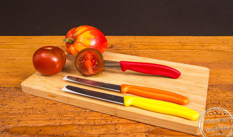 Victorinox Tomatenmesser mit Gravur auf Holzbrett neben Tomaten – perfektes Werbemittel für Küche und Genuss.