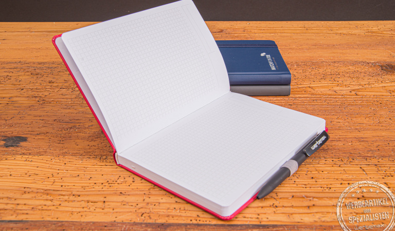 Aufgeschlagenes Notizbuch mit Stifteschlaufe und Mikroperforation. So können die Notizen einfach weitergegeben oder abgeheftet werden. Das universelle Winkelkaro ist für deutsche Kunden oder Mitarbeiter perfekt. 