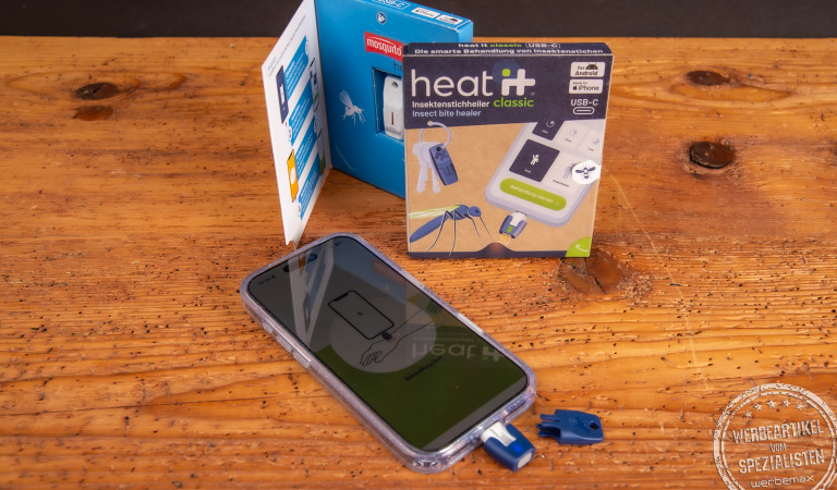 heat it Insektenstichheiler am Smartphone mit Verpackung – chemiefreies Werbegeschenk für Outdoor, Reisen und Sommer.