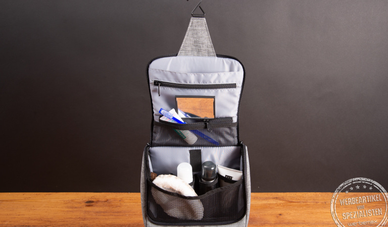 Offener reisenthel Kulturbeutel im twist silver Design mit Haken zum Aufhängen, mehreren Netzfächern und Pflegeartikeln wie Zahnbürste, Deo und Duschgel – praktischer Reise- und Werbeartikel für unterwegs.