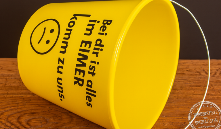 Gelber Kunststoff-Eimer mit dem frechen Aufdruck ‚Bei dir ist alles im Eimer – komm zu uns‘, genutzt als aufmerksamkeitsstarker Werbeartikel für Azubimessen.