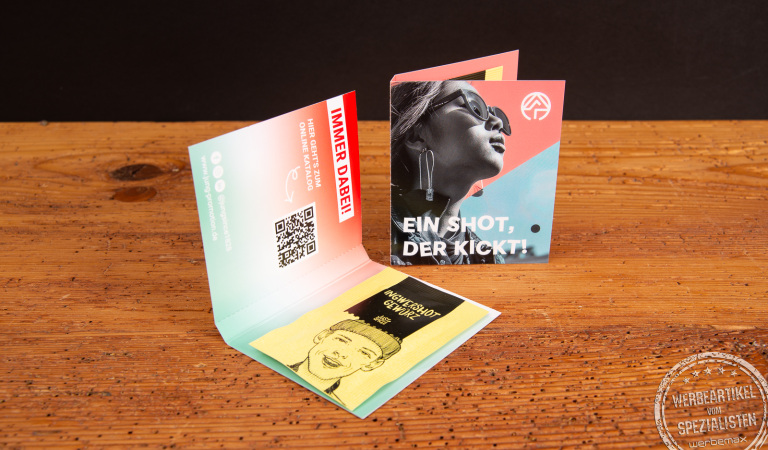 Werbekarte Midi Just Spices mit Avocado Topping als individuell bedruckter Werbeartikel; geöffnete Gewürzkarten als moderne Messe-Giveaways auf Holztisch, ideal zum Werbeartikel bedrucken.