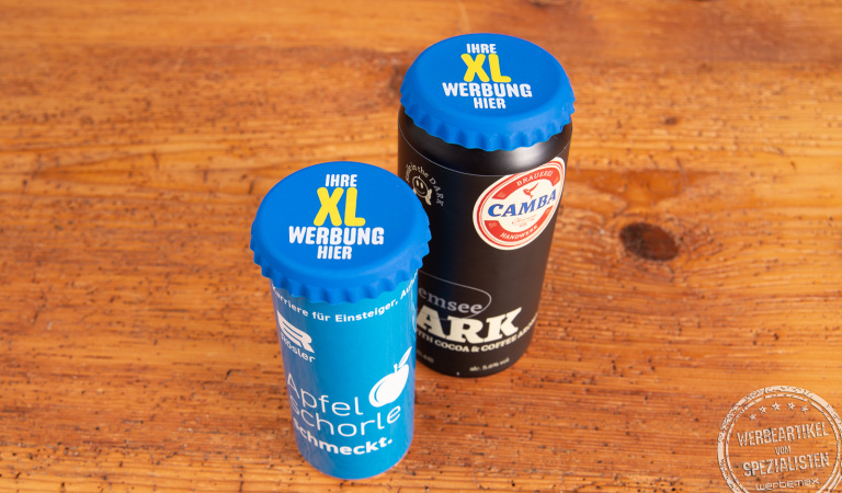 2 blaue, bedruckte XL Korki Can Silikon-Dosendeckel auf Getränkedosen als praktisches Merch für Festivals, Events und Messen auf Holztisch stehend