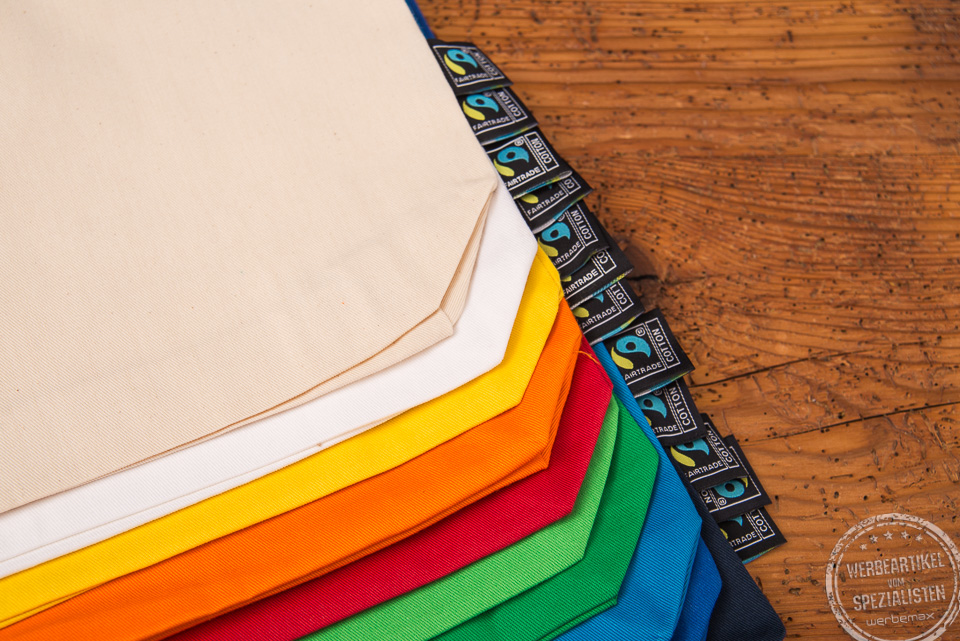 Detailaufnahme der nachhaltigen Baumwolltasche Edda mit Fairtradelabel an der Seite auf Holztisch.