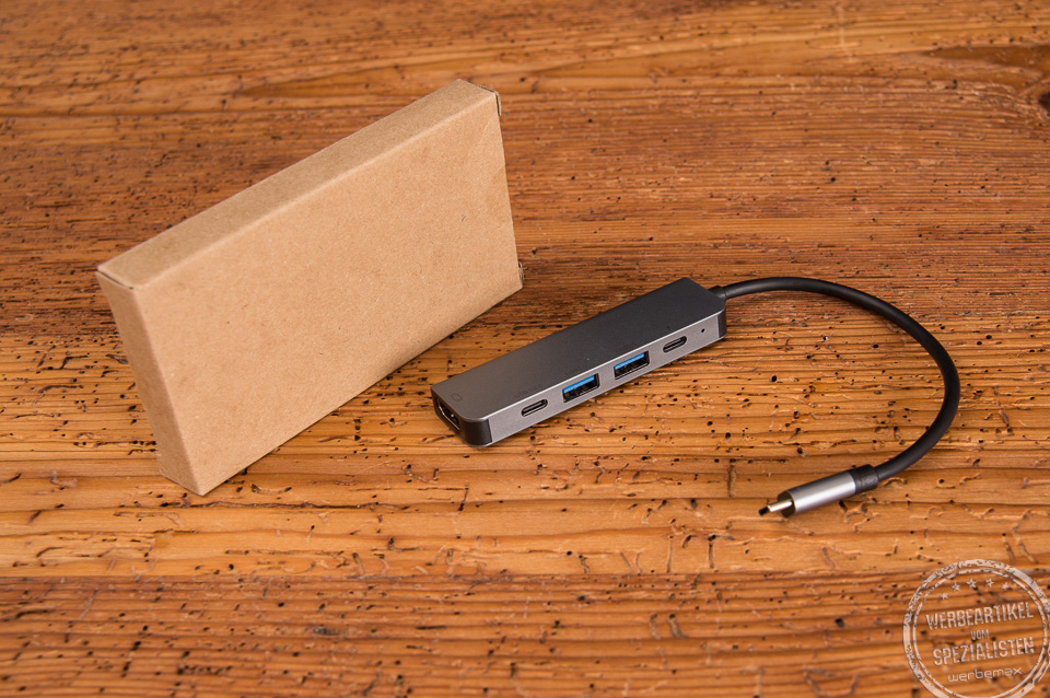 Verpackung des USB-C Hub aus Kraftpapierkarton mit dem USB-C Hub daneben